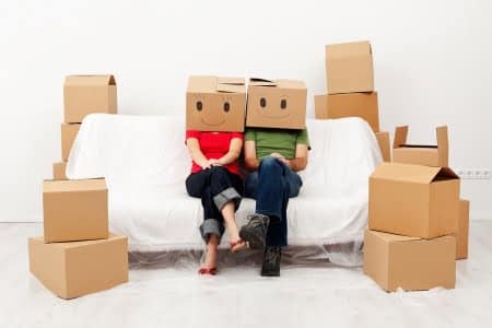 16890862 - couple in their new home with cardboard boxes, sitting on covered sofa